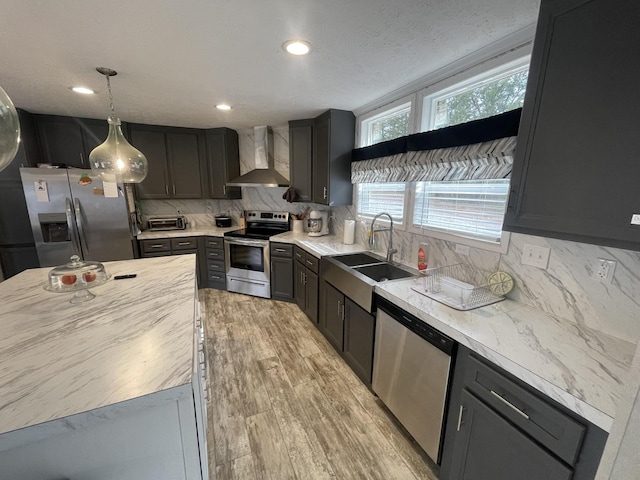 kitchen with stainless steel appliances, tasteful backsplash, wall chimney exhaust hood, and decorative light fixtures