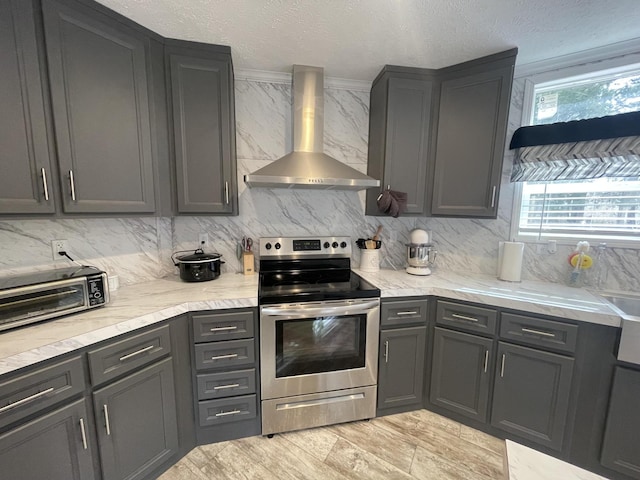 kitchen with backsplash, wall chimney range hood, stainless steel electric range, and a textured ceiling