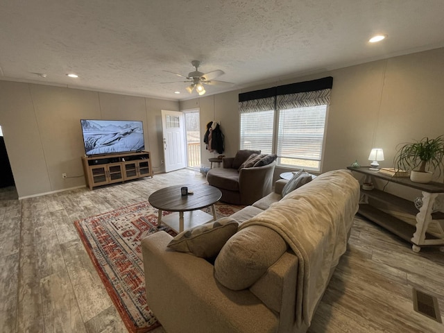 living area with a textured ceiling, recessed lighting, wood finished floors, visible vents, and a ceiling fan