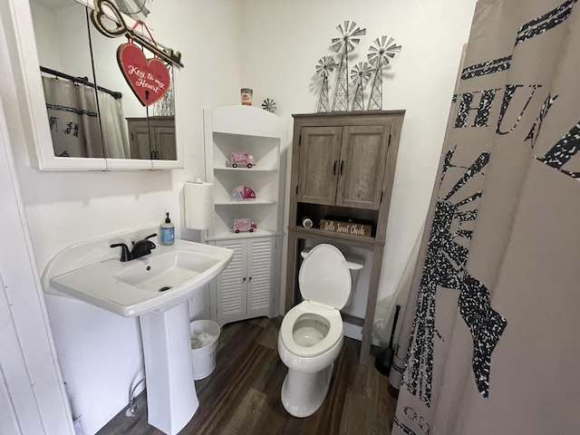 bathroom featuring toilet, a sink, wood finished floors, and a shower with shower curtain