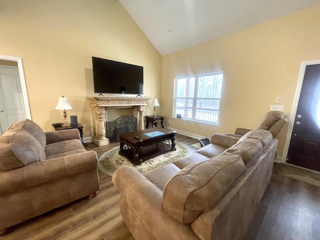 living room with high vaulted ceiling, a fireplace, baseboards, and wood finished floors