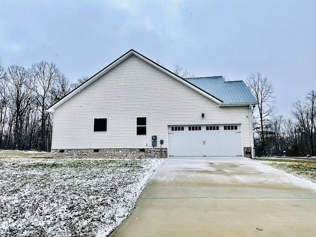 view of snowy exterior featuring a garage, crawl space, metal roof, and driveway