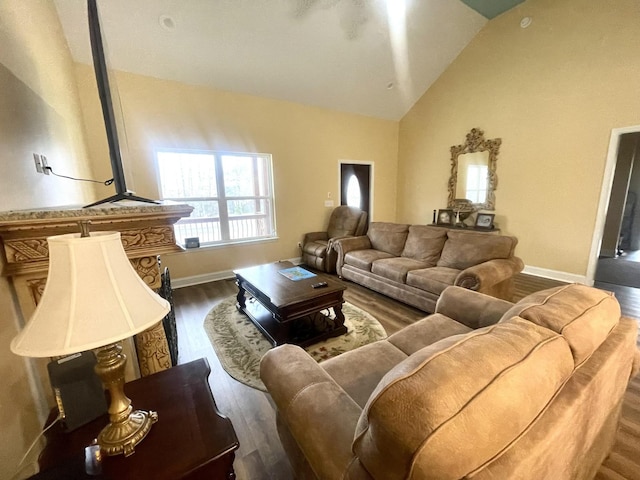 living room featuring dark wood-type flooring, vaulted ceiling, and baseboards