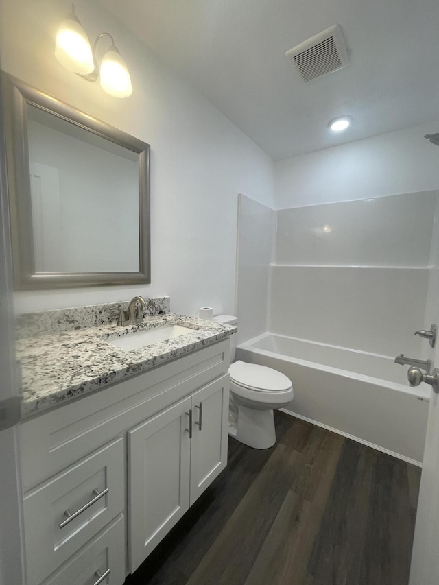 bathroom featuring toilet, wood finished floors, vanity, visible vents, and shower / bathing tub combination