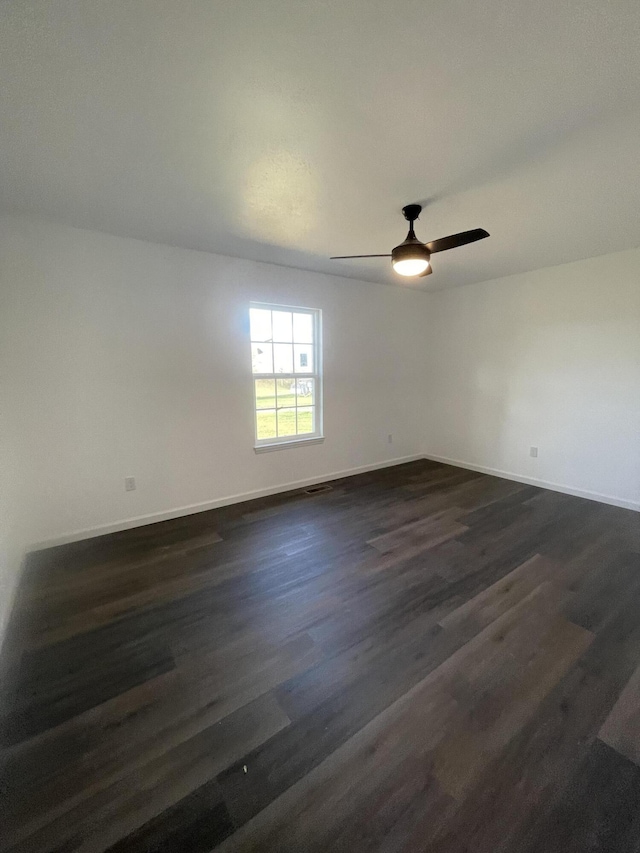 unfurnished room featuring dark wood-type flooring, baseboards, and a ceiling fan