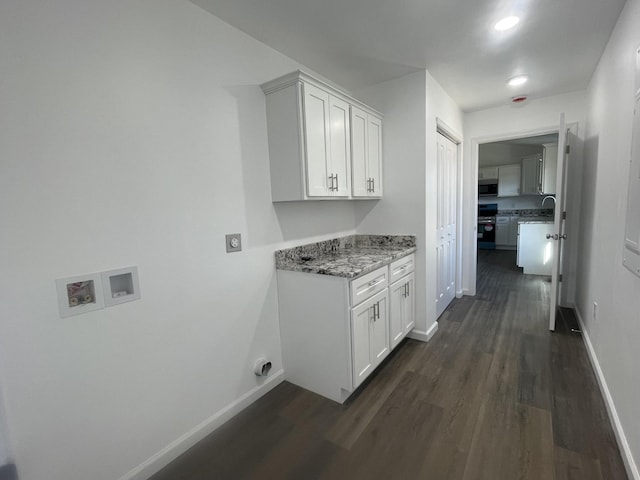 laundry room featuring dark wood finished floors, hookup for a washing machine, cabinet space, and baseboards