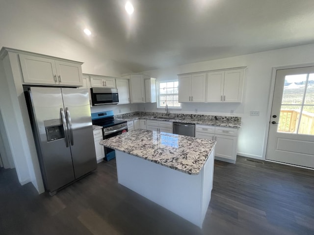 kitchen featuring light stone countertops, white cabinetry, appliances with stainless steel finishes, and a center island