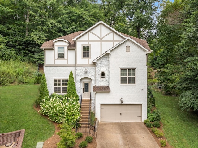 tudor home with stucco siding, a shingled roof, a garage, driveway, and a front lawn