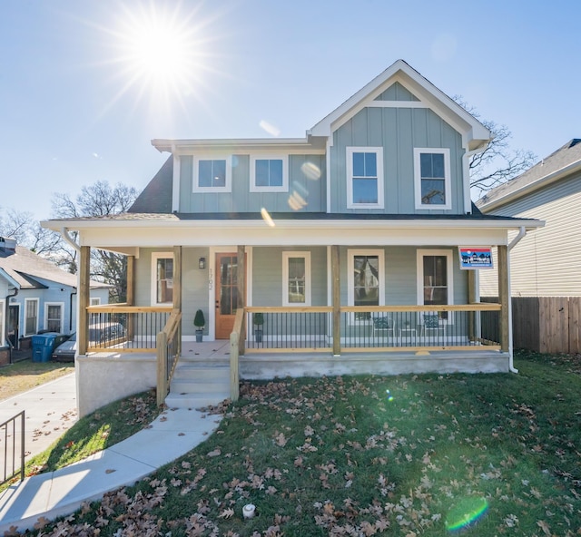 country-style home featuring covered porch, a front lawn, and board and batten siding