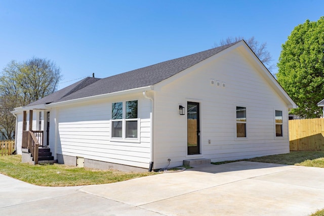 view of front of house with a shingled roof, a patio area, and fence