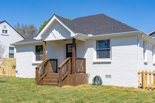 rear view of house with crawl space, brick siding, a lawn, and roof with shingles