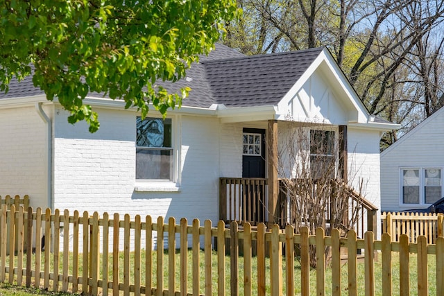 view of front of property with brick siding, roof with shingles, and fence