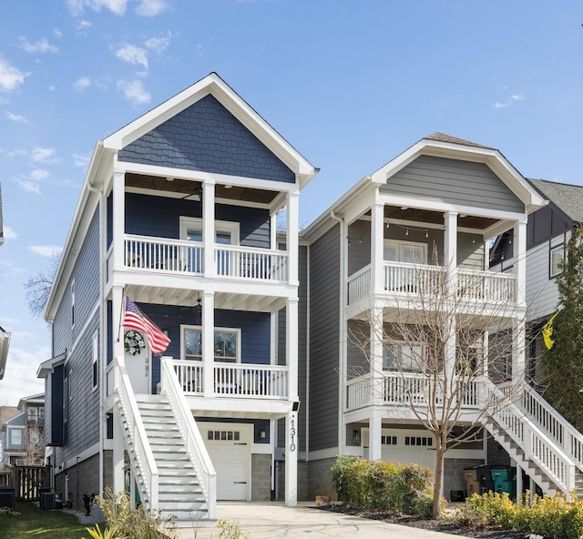 view of front of home with a porch, stairway, an attached garage, and a balcony