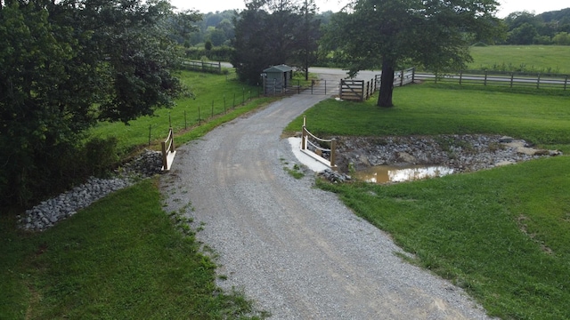 view of community with a water view, fence, a lawn, and a rural view