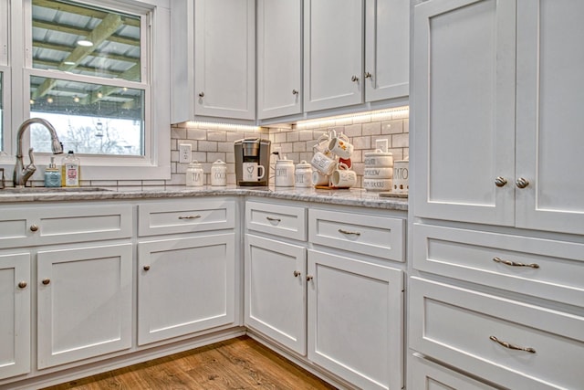 23 Hickman Hwy, Gordonsville, TN 38563 - kitchen with light stone counters, light wood finished floors, tasteful backsplash, white cabinets, and a sink
