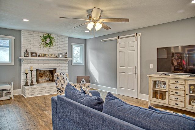 23 Hickman Hwy, Gordonsville, TN 38563 - living room featuring ceiling fan, a barn door, wood finished floors, baseboards, and a brick fireplace