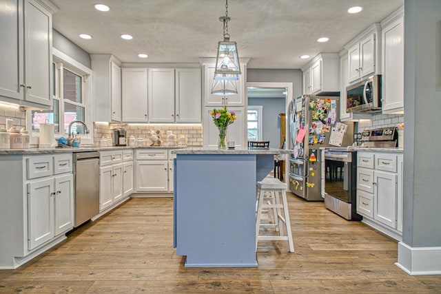 23 Hickman Hwy, Gordonsville, TN 38563 - kitchen featuring white cabinets, appliances with stainless steel finishes, a breakfast bar area, a center island, and pendant lighting