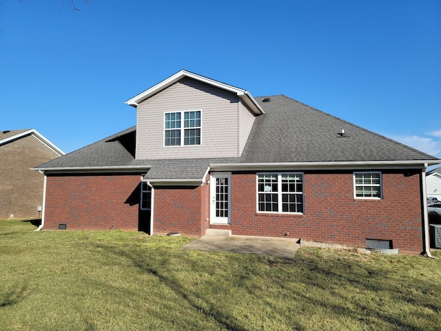 rear view of property featuring roof with shingles, crawl space, a yard, a patio area, and brick siding