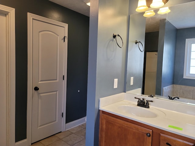 bathroom featuring a textured ceiling, vanity, baseboards, and tile patterned floors