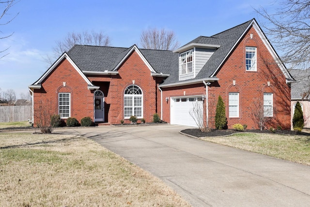 traditional-style home with driveway, brick siding, an attached garage, and a shingled roof