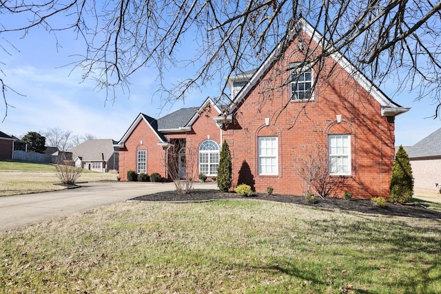 traditional-style house featuring a front lawn and brick siding