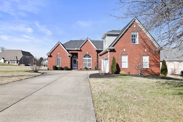 traditional-style home featuring driveway, roof with shingles, a front yard, and brick siding