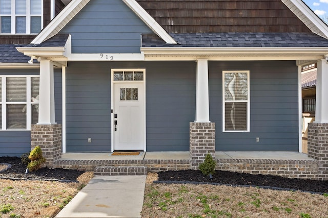 doorway to property with a porch and roof with shingles