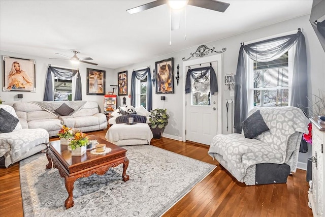 living room with dark wood-style flooring, ceiling fan, and baseboards