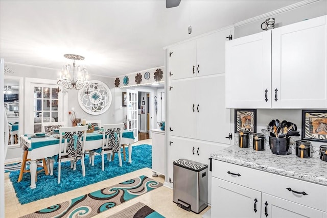 kitchen with white cabinetry, hanging light fixtures, a notable chandelier, and light stone countertops