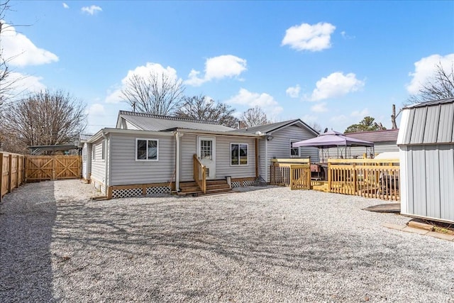 rear view of property with metal roof, a gazebo, and fence