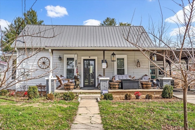 view of front facade with covered porch, metal roof, and a front yard