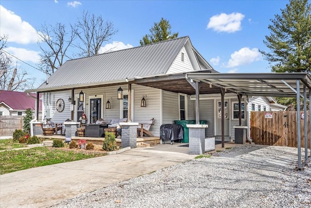 view of front of property with covered porch, fence, and metal roof