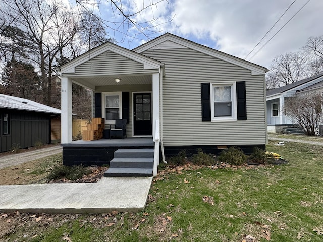 bungalow-style home featuring covered porch and a front lawn