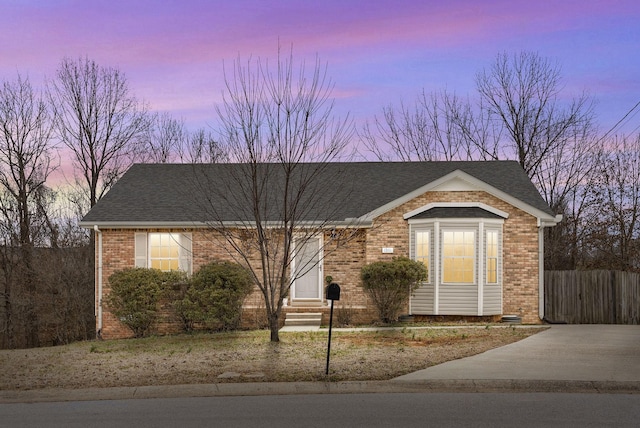 ranch-style home with entry steps, a shingled roof, and brick siding