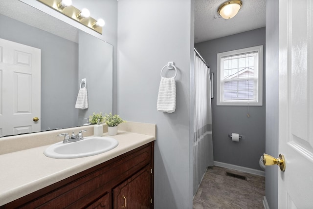 bathroom featuring a textured ceiling, vanity, visible vents, and baseboards