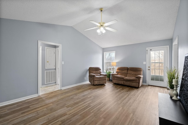 sitting room with lofted ceiling, ceiling fan, a textured ceiling, wood finished floors, and baseboards