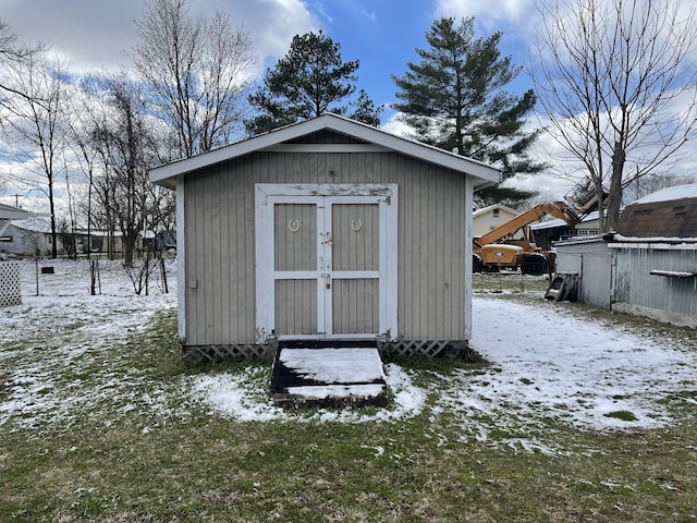 snow covered structure featuring an outbuilding and a storage unit