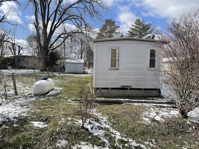 snow covered property with an outbuilding and a storage unit