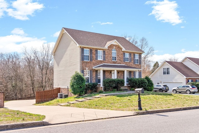 colonial inspired home with brick siding, fence, a front yard, cooling unit, and a garage