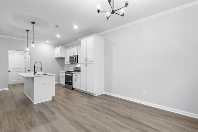 kitchen featuring appliances with stainless steel finishes, decorative light fixtures, a center island with sink, and white cabinetry