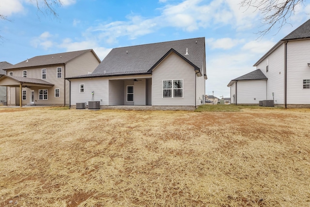 back of house featuring central AC unit and a lawn