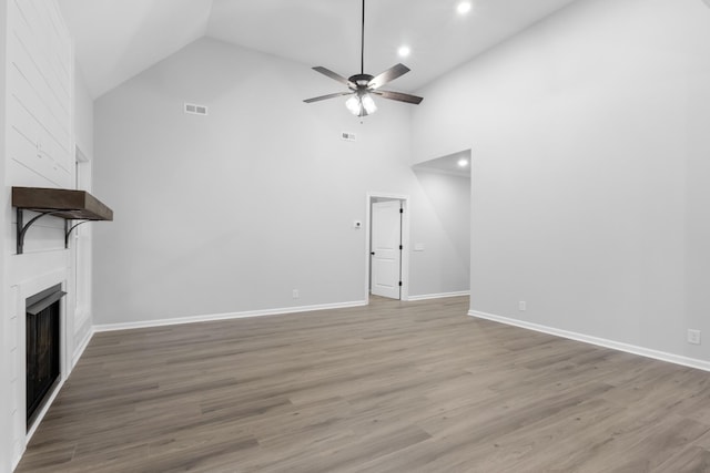 unfurnished living room with ceiling fan, a fireplace, wood finished floors, visible vents, and baseboards