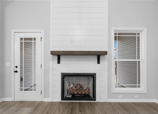 unfurnished living room featuring a fireplace, baseboards, and wood finished floors