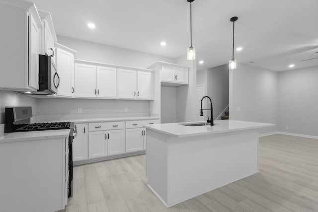 kitchen with white cabinets, light countertops, a kitchen island with sink, and stainless steel appliances