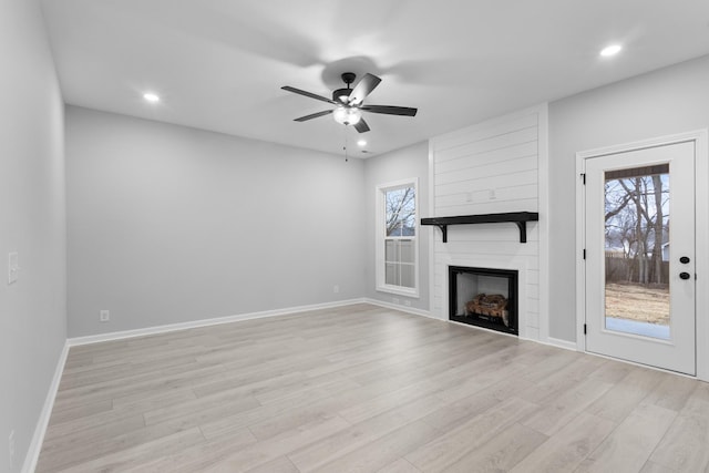 unfurnished living room featuring baseboards, a fireplace, and light wood finished floors