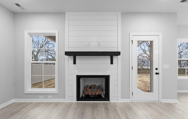 unfurnished living room with light wood-style floors, visible vents, a fireplace, and baseboards