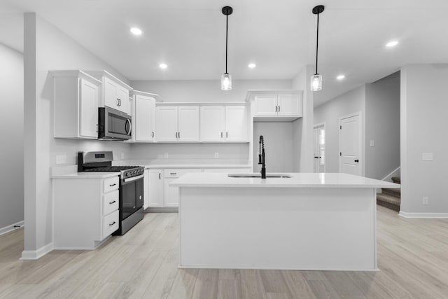 kitchen with an island with sink, white cabinetry, stainless steel appliances, and light countertops