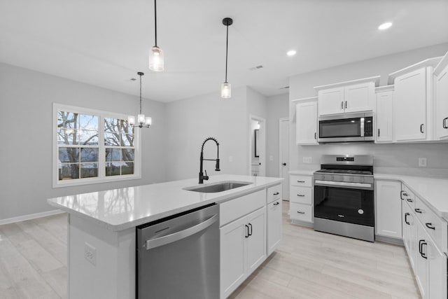 kitchen featuring a center island with sink, light countertops, appliances with stainless steel finishes, white cabinets, and a sink