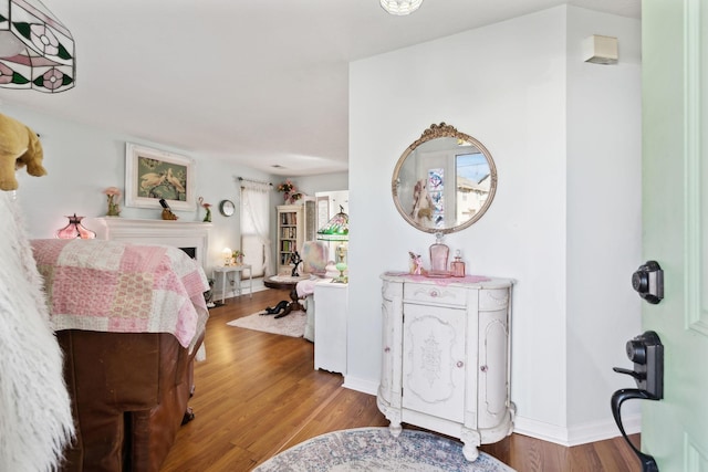 bedroom featuring a fireplace, baseboards, and wood finished floors