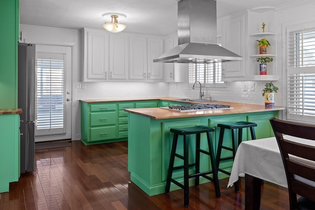 kitchen with a breakfast bar, open shelves, green cabinetry, a peninsula, and extractor fan